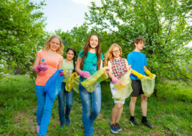 Teenagers wear gloves and carry garbage bag